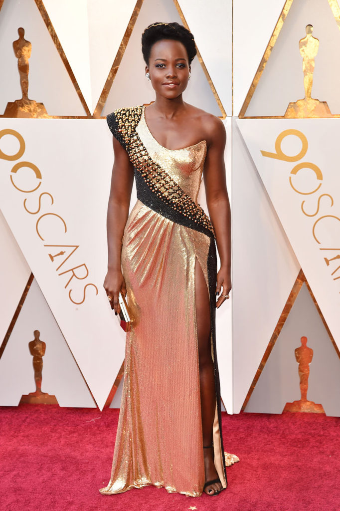 Lupita Nyong’o  en une robe de soirée dorée longue asymétrique avec fente